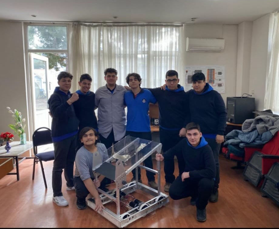 Atölyede robotla birlikte poz veren Sardis Robotics takımı.